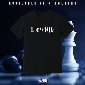 May include: Black t-shirt with white text that reads "1. e4 Nf6". The shirt is photographed against a blue and white chessboard background.