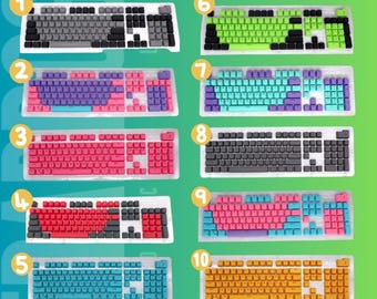 Peut inclure: Dix claviers mécaniques avec différents jeux de touches colorées sont présentés. Les claviers ont diverses combinaisons de couleurs, notamment le gris, le violet, le rose, le rouge, le bleu, le vert et le jaune. Chaque clavier est dans un plateau en plastique transparent.