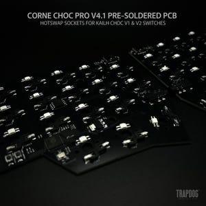以下が含まれることがあります： 白のホットスワップソケットを備えた、黒色のプリはんだ付けPCBのクローズアップ。テキスト「CORNE CHOC PRO V4.1 PRE-SOLDERED PCB」と「HOTSWAP SOCKETS FOR KAILH CHOC V1 & V2 SWITCHES」が表示されています。 TRAPDOGのロゴが右下にあります。