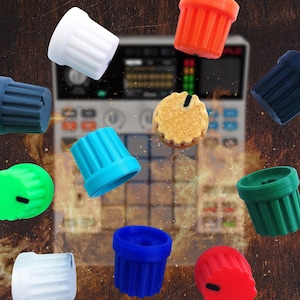 May include: A collection of eleven cylindrical control knobs in various solid colours including white, orange, dark blue, light blue, green, and red, featuring vertical ridges and a small black indicator line, floating above a blurred music sampler.