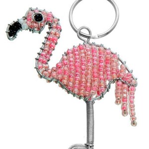 Könnte beinhalten: Rosa Perlen-Flamingo-Schlüsselanhänger mit einem silbernen Federring. Der Flamingo besteht aus Draht und Perlen und hat einen langen Hals und lange Beine.