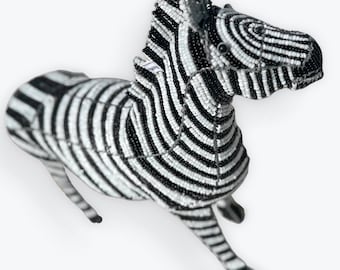 Puede incluir: Figurita de cebra artesanal, meticulosamente adornada con cuentas negras y blancas. El cuerpo de la cebra presenta rayas verticales audaces, con una cabeza y patas detalladas. Una pieza decorativa única para la decoración del hogar.
