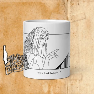 May include: White ceramic mug featuring a black and white line drawing of a woman with a finger pointed forward. The text "You look lonely..." is printed below the illustration. The mug has a minimalist design.