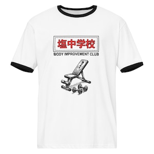 Pode incluir: Camiseta branca com detalhes pretos. Apresenta um esboço de um banco de pesos e halteres, com texto em japonês e inglês: "BODY IMPROVEMENT CLUB".