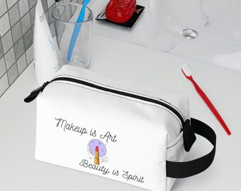 May include: White canvas makeup bag with a black zipper and handle. The bag features a graphic of a lipstick with the text "Makeup is Art, Beauty is Spirit".