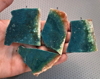 May include: Four irregular, flat stone slices labeled 1 through 4, featuring a deep teal and green color palette with white speckled inclusions and rough, light-colored edges. Each piece displays a unique, natural mineral texture and pattern.