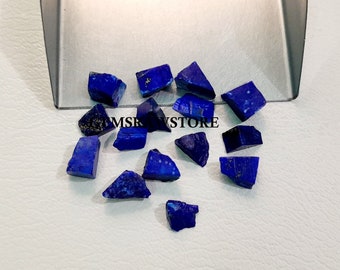 Könnte beinhalten: Eine Sammlung von rohen, dunkelblauen Lapislazuli-Edelsteinen. Die Steine sind in verschiedenen Größen und Formen, einige zeigen einen Hauch von goldenen Flocken.