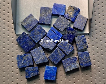 Könnte beinhalten: Eine Sammlung rechteckiger Lapis Lazuli-Edelsteine mit goldenen Einschlüssen. Die tiefblauen Steine liegen in einer silbernen Schale. Der Text "GemsRawStore" ist im Bild zu sehen.