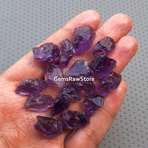 May include: A collection of raw amethyst crystals in various sizes and shapes. The crystals are a deep purple colour and have a natural, rough texture.