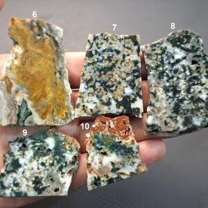 May include: A collection of five rough-cut, natural stone slabs. The stones display a variety of colors, including green, white, brown, and yellow. Each stone has a unique pattern and texture, showcasing the natural beauty of the material.