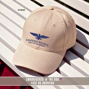 Stone color embroidered United States 250th anniversary cap with eagle emblem, flat lay showing front embroidery detail.