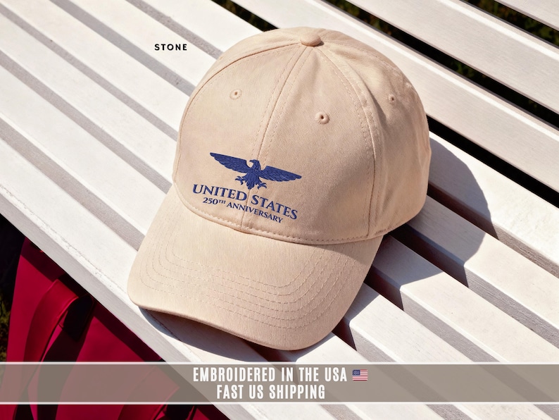 Stone color embroidered United States 250th anniversary cap with eagle emblem, flat lay showing front embroidery detail.