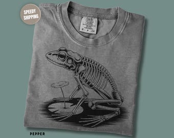 Camiseta Comfort Colors com estampa de esqueleto de sapo gótico, estilo Dark Academia, inspirada em biologia.