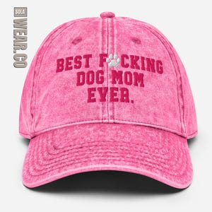 Peut inclure: Casquette de baseball rose d&eacute;lav&eacute;e avec le texte "BEST F*CKING DOG MOM EVER." en lettres rouges et une empreinte de patte blanche.