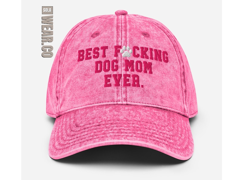 Peut inclure: Casquette de baseball rose d&eacute;lav&eacute;e avec le texte "BEST F*CKING DOG MOM EVER." en lettres rouges et une empreinte de patte blanche.
