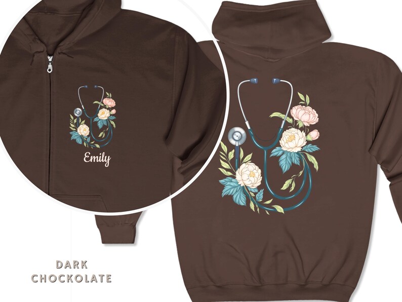 Pu&ograve; includere: Felpa con cappuccio con zip di colore cioccolato scuro con stetoscopio e design floreale. Il testo "Emily" &egrave; ricamato sulla parte anteriore della felpa.