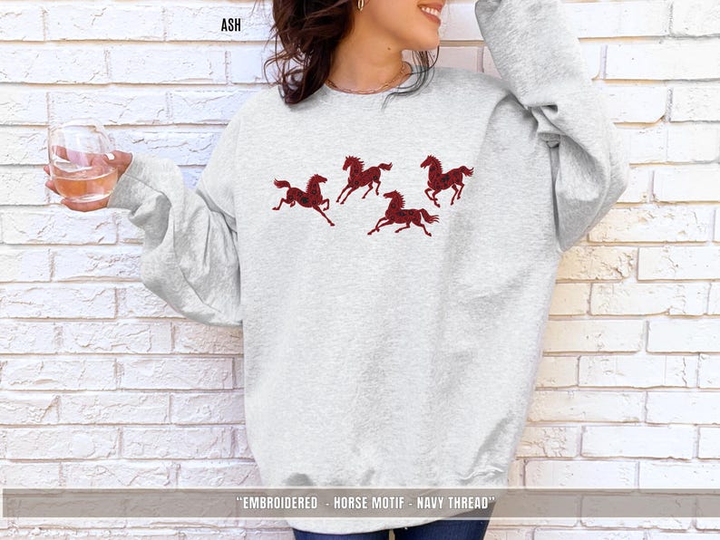 Ash grey unisex sweatshirt with maroon & black embroidered horse design shown in lifestyle setting