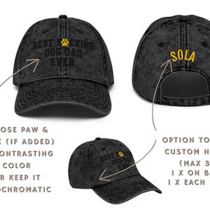 Peut inclure: Casquette de baseball en denim noir avec le texte "Best F*cking Dog Dad Ever" brod&eacute; en blanc. La casquette a une empreinte de patte jaune brod&eacute;e au-dessus du texte. Le dos de la casquette a le mot "SOLA" brod&eacute; en jaune.