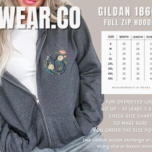 Pu&ograve; includere: Una felpa grigia con zip integrale con un design floreale e uno stetoscopio. La tabella delle taglie mostra le misure in pollici per le taglie S a 5XL. Il testo "FOR OVERSIZED LOOK GO UP - AT LEAST 2 SIZES CHECK SIZE CHART TO MAKE SURE YOU ORDER THE SIZE YOU WANT (we cannot accept exchange or refunds for wrong size or buyers remorse)" &egrave; stampato sotto la tabella delle taglie.