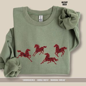 Military green sweatshirt with maroon & black embroidered horse design shown in flat lay view