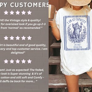 Happy Customers five-star review slide for the Funny Cat Shirt, featuring an Ivory Comfort Colors lifestyle image with the I Am at Capacity and in my feral era cat graphic tee, reassuring shoppers about quality, fit, customer service, and giftability.