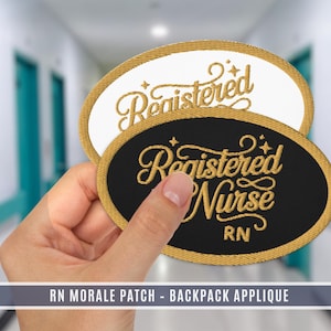 Può includere: Toppe ovali con bordi dorati e testo dorato. Una è nera con "Registered Nurse RN", l'altra bianca con "Registered". Le toppe sono presentate su uno sfondo sfocato.