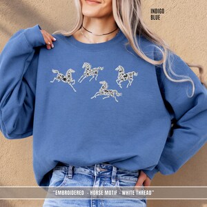 Indigo blue sweatshirt with white & black embroidered horses styled for a relaxed unisex look