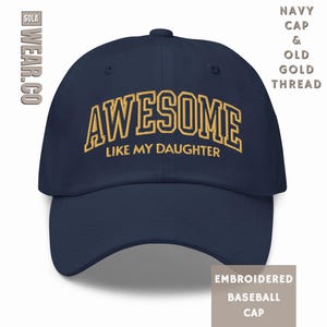 May include: A navy blue baseball cap with the text "AWESOME LIKE MY DAUGHTER" embroidered in gold thread.