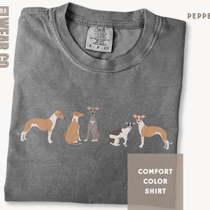 May include: A pepper-colored t-shirt featuring a graphic of five dogs in various poses. The shirt has a crew neckline and a Comfort Colors label at the neck. The text SOLA WEAR.CO is visible on the left, and the text COMFORT COLOR SHIRT is in a box.