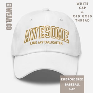 May include: White baseball cap with "AWESOME LIKE MY DAUGHTER" embroidered in old gold thread. The cap features a curved brim and a classic six-panel design. The brand logo "WEAR.CO" is visible on the side.