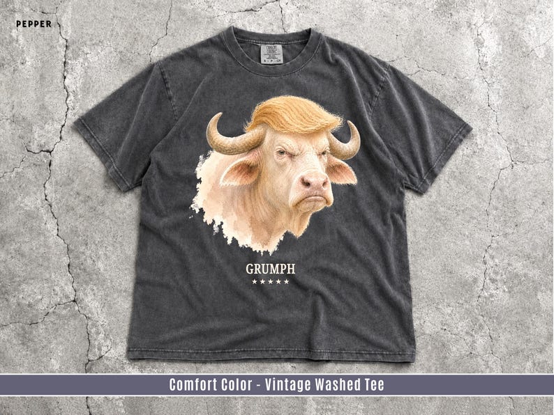 Pepper Comfort Colors GRUMPH albino buffalo trump look alike graphic T-shirt flat lay on grunge concrete background.
