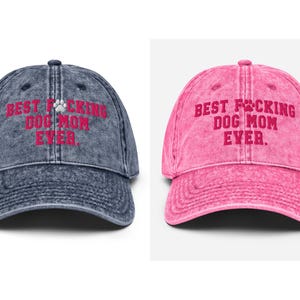 Peut inclure: Deux casquettes de baseball de style vintage avec le texte "Best F*cking Dog Mom Ever." Une casquette est en denim bleu et l'autre est rose.