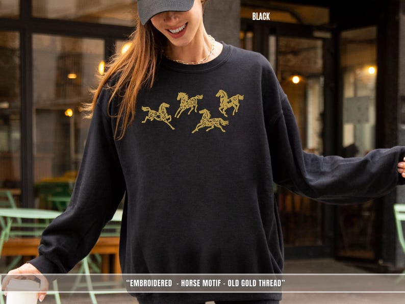 Woman wearing black embroidered horse sweatshirt with gold thread showing relaxed unisex fit
