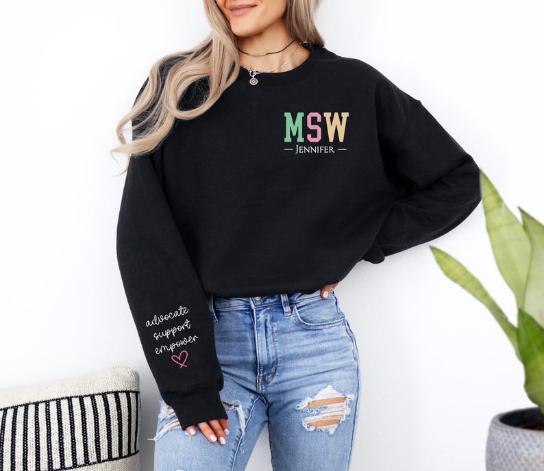 May include: Black sweatshirt with the text "MSW - JENNIFER -" in colorful letters. The left sleeve has the text "advocate support empower" with a pink heart.