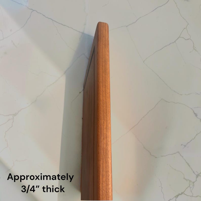 May include: A rectangular wooden cutting board shown from a side profile angle. The board features a smooth, natural brown wood grain finish and a straight edge. The text on the image indicates that the board is approximately 3/4 inches thick.