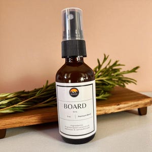 May include: A brown glass spray bottle of board oil with a black pump top. The white label features the text RUGGED, BOARD OIL, 2 oz., Premium Blend, and lists ingredients including fractionated coconut oil, beeswax, and carnauba wax.
