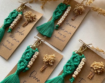 May include: Four green and white tassel keychains with personalized wooden beads spelling out the names Sadia, Corinne, Dana, and Faiza. Each keychain is displayed on a brown card with the text "Thank you for being my Bridesmaid".