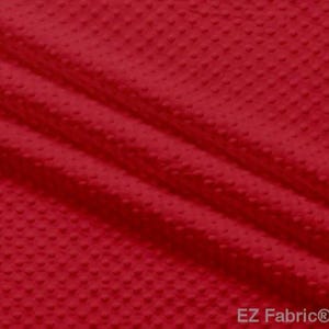 May include: Close-up of a vibrant red fabric with a textured, dotted pattern. The material is folded, creating diagonal lines and shadows that highlight the fabric's texture. The fabric appears soft and pliable, suitable for various crafting projects.