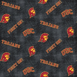 May include: A black and white fabric pattern with the words "USC Trojans" and "Fight On!" repeated throughout. The pattern also features a red and gold helmet with a Spartan warrior's face.