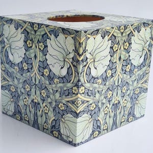 Peut inclure: Boîte à mouchoirs carrée avec un motif floral composé de fleurs blanches, de feuilles vertes et d'accents jaunes sur un fond bleu foncé.