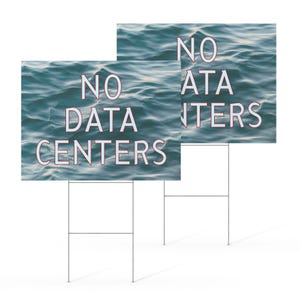 May include: Two yard signs with the text "NO DATA CENTERS" in white letters. The background of the signs is a teal water pattern. The signs are mounted on metal stakes.