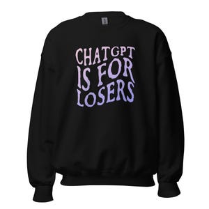 May include: A black long-sleeve sweatshirt featuring the text CHATGPT IS FOR LOSERS printed in a wavy, distorted font. The lettering transitions in colour from a soft pink at the top to a light purple at the bottom, centred on the chest.