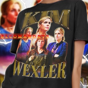 May include: A black t-shirt featuring a gold graphic print of a woman's face and the text "KIM WEXLER".