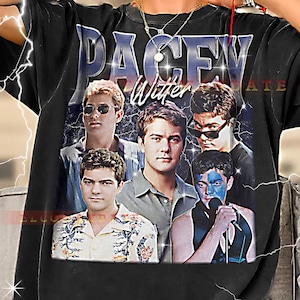 May include: Black t-shirt featuring a graphic of five men with the text "PACEY Witter" in a blue and white font. The image has a vintage, retro style with lightning bolt accents.