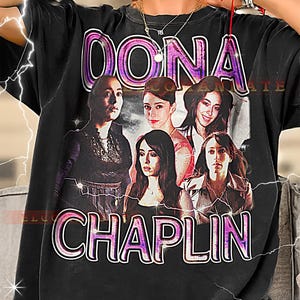 May include: Black t-shirt featuring a graphic of five women with the text "OONA CHAPLIN" in a purple and white outlined font. The design has a vintage, distressed look.