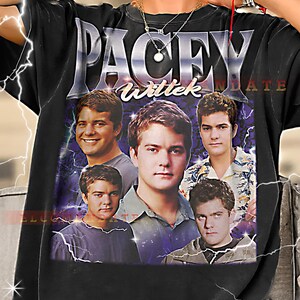 May include: Black t-shirt featuring a graphic of the word "PACEY" above a collage of five men's faces. The word "Wittek" is below "PACEY". The background has a purple and blue lightning design.
