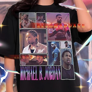 May include: Black oversized t-shirt with a collage of images and the text "ELCOMANDATE" and "MICHAEL B. JORDAN" in pink and white. The shirt is worn by a person. The shirt is a unisex style.