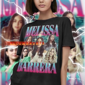May include: Black t-shirt featuring a graphic of Melissa Barrera with the text "MELISSA BARRERA" in a retro font. The design includes multiple images of the actress. The background has a lightning bolt effect.