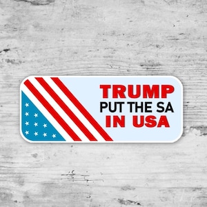 May include: A rectangular sticker with a light blue background and rounded corners. The left side features a design of the American flag. The text "TRUMP PUT THE SA IN USA" is in red and black.