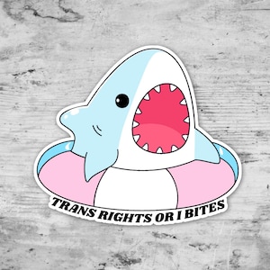 May include: A white shark with a pink inner tube and an open mouth, with the text "Trans Rights or I Bites" on the bottom.